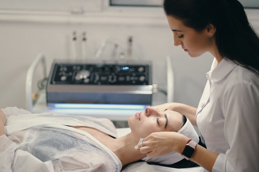A female cosmetologist administering a facial treatment for a patient.