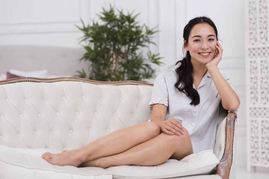 A woman with smooth legs sits on a couch.